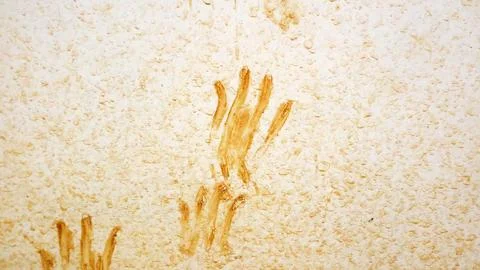 Brown handprints smeared on rough white wall texture, abstract background w.. Stock Photos