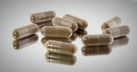 Brown herbal tablets on spinning reflective turntable. 4k video Stock Footage 146262398