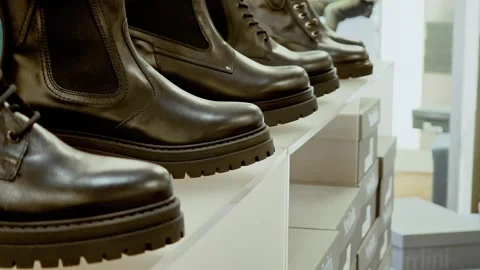 Brown leather boots on white shelves of shoe boutique. Retail display with Stock Footage 324928147
