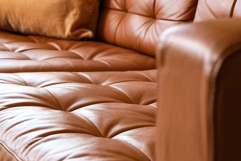Brown leather sofa with tufted cushions and a soft pillow, comfortable home f Stock Photos