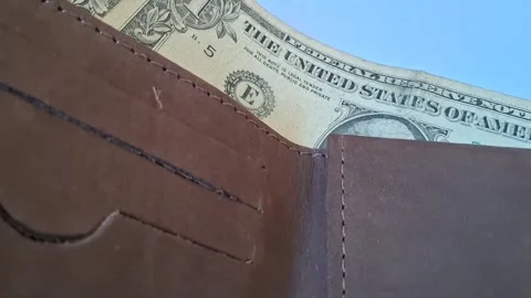 Brown leather wallet displaying multiple american dollar bills in motion footage Stock Footage 339302172