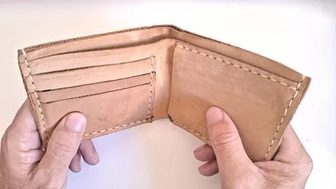 Brown leather wallet held open by hands against white background Stock Photos
