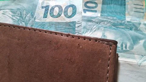 Brown leather wallet holding multiple brazilian one hundred real banknotes Stock Photos