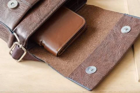 Brown leather wallet inside small shoulder bag. Stock Photos