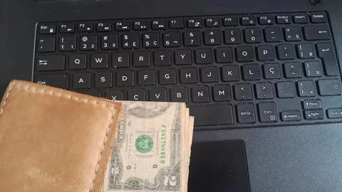 Brown leather wallet with two dollar bill on black keyboard Stock Photos
