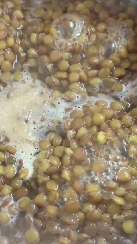 Brown lentils boiling in water inside a metal pot Stock Footage 331973566