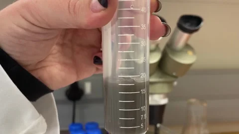 Brown liquid being poured into measuring test tube Stock Footage 315761540