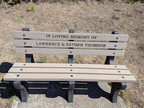 A brown memorial bench “In loving memory of Lawrence and Esther Thomson” Fotos Stock