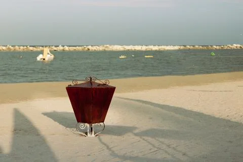 Brown metal garbage container on the empty see beach outdoor. Vacation concept. Stock Photos