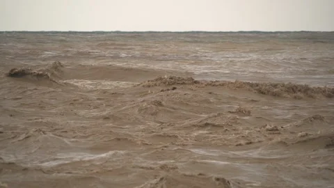 Brown muddy waves churn at river mouth where floodwaters meet - Current Collides Stock Footage 339709776