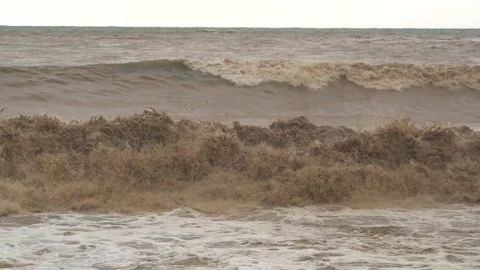 Brown muddy waves churn at river mouth where floodwaters meet - Coastal Current Stock Footage 339736358
