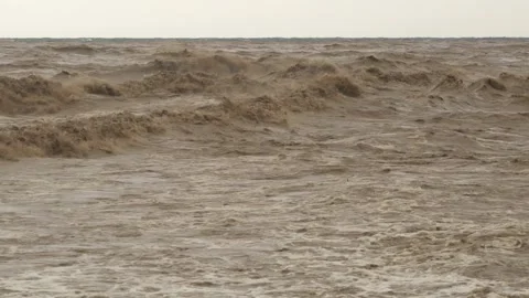 Brown muddy waves churn at river mouth where floodwaters meet - Ocean Collision Stock Footage 339743888