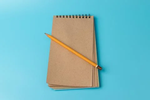 Brown notebook,pencil, on blue background. top view copy space Stock Photos