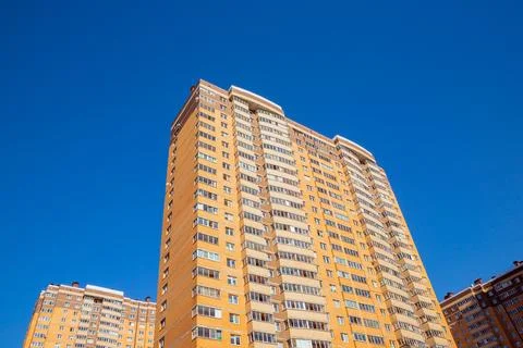 Brown orange brick wall of multi-storey apartment building on blue sky Stock Photos