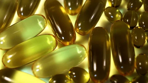 Brown oval capsules of large and small fat-soluble vitamins on a white backgroun Stock Footage 145108170