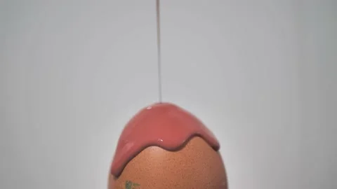 Brown paint slowly pours onto the Easter egg. High quality HD video. Feathers Stock Footage 223385031