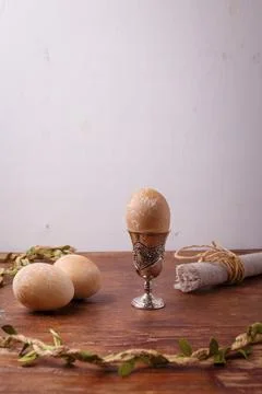 Brown painted Easter egg in silver egg cup on rustic table, white background Stock Photos