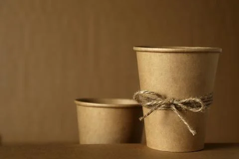 Brown paper cups tied with string sit on a table against a brown background in a Stock Photos