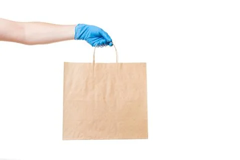 A brown paper eco friendly package holds the hand of a deliveryman. Stock Photos