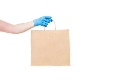 Brown paper eco friendly package holds hand of deliveryman in sterile glove. Stock Photos