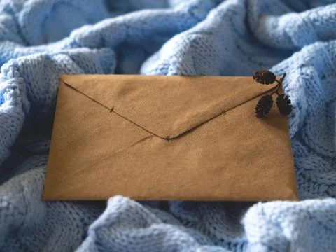 The brown paper envelope on the pale blue wool knitted background. Stock Photos