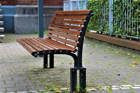 Brown park bench on a paved surface Stock Photos