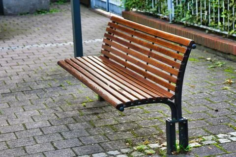 Brown park bench on a paved surface Stock Photos