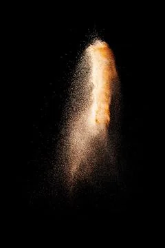 Brown particles exploding on black background, brown dust splashing 写真素材