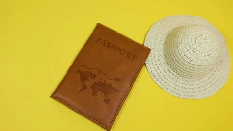 Brown passport and hat falling on yellow background Stock Footage 287437579