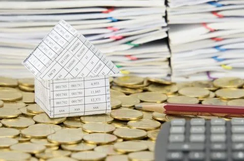 Brown pencil and house on stack of gold coins Stock Photos