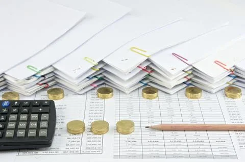 Brown pencil with black calculator between Pile of gold coins Stock Photos