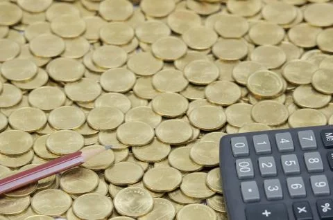Brown pencil with black calculator on stack of gold coins Stock Photos
