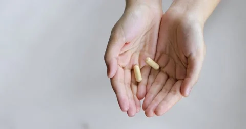 Brown pills falling in woman's palms hands on white background, closeup view. Stock Footage 145446290