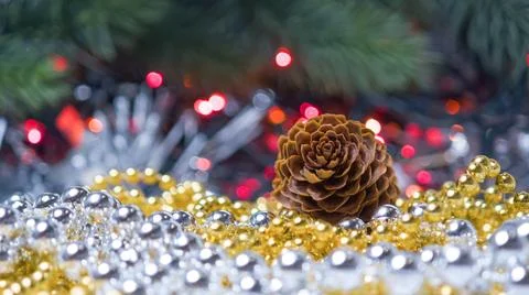 Brown pine cone resting on shiny gold and silver bead garlands with blurred.. Stock Photos