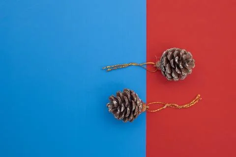 Brown pine cones with golden string loops on a vibrant blue and red backgroun Stock Photos