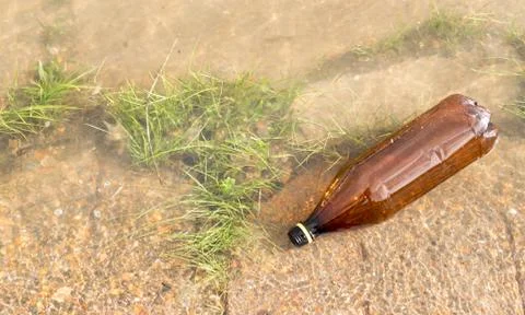 Brown Plastic Bottle in River Stock Photos
