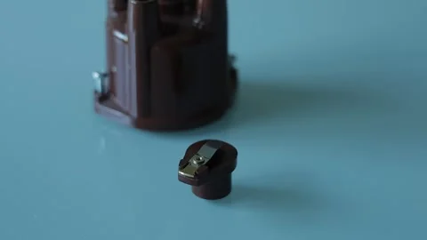 A brown plastic distributor cap with five spark plug terminals paired with its Stock Footage 340109863