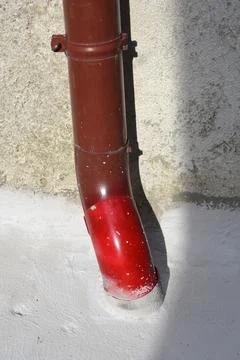 Brown plastic gutter downspout pipe on stucco wall Stock Photos