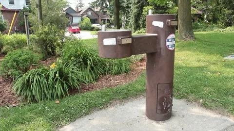 Brown public double water drinking fountain with second leveraged out on cement Stock Footage 247749230