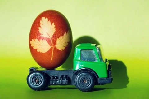 Brown-red Easter grass decorated egg on green toy car Stock Photos