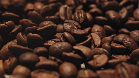 Brown roasted coffee grains beans gyrating in a black tray Stock Footage 139689822