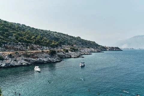 Brown rocks and sharp stones in the greenish blue water of Aegean sea near the Stock Photos