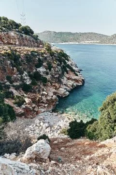Brown rocks and sharp stones in the greenish blue water of Aegean sea near the Stock Photos
