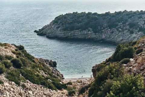 Brown rocks and sharp stones in the greenish blue water of Aegean sea near the Stock Photos
