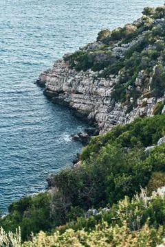Brown rocks and sharp stones in the greenish blue water of Aegean sea near the Stock Photos