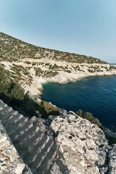 Brown rocks and sharp stones in the greenish blue water of Aegean sea near the Stock Photos