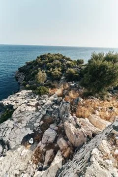 Brown rocks and sharp stones in the greenish blue water of Aegean sea near the Stock Photos