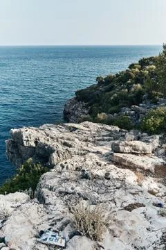 Brown rocks and sharp stones in the greenish blue water of Aegean sea near the Stock Photos