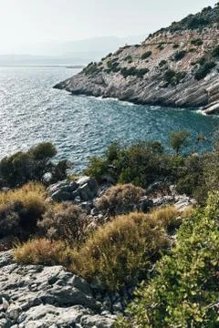 Brown rocks and sharp stones in the greenish blue water of Aegean sea near the Stock Photos