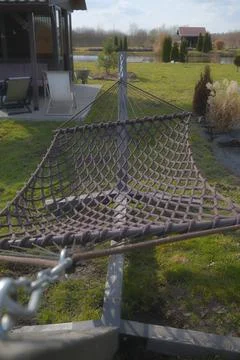 Brown rope hammock standing in a backyard garden during the daytime Stock Photos